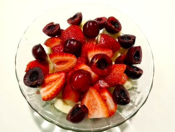 Fresh mango, strawberries, oranges, cherries, and banana gently combined in a large bowl.