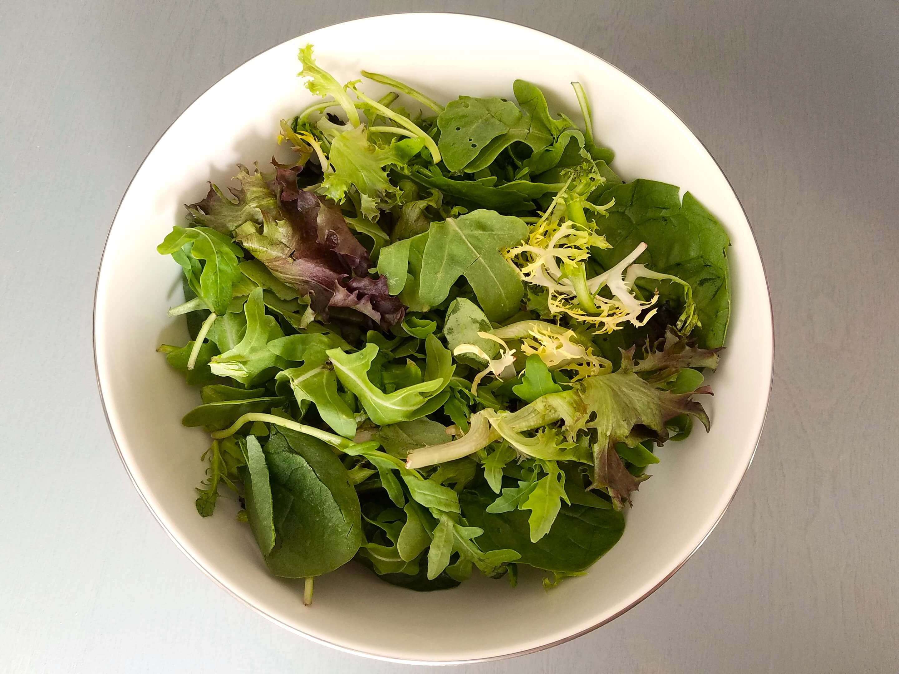 Baby arugula, mixed greens, baby lettuce, and fresh mint in a salad bowl.