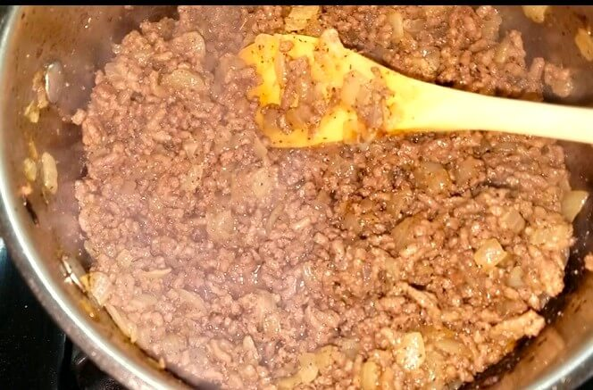 Minced beef and diced onion cooking with nutmeg and cardamom in a pan