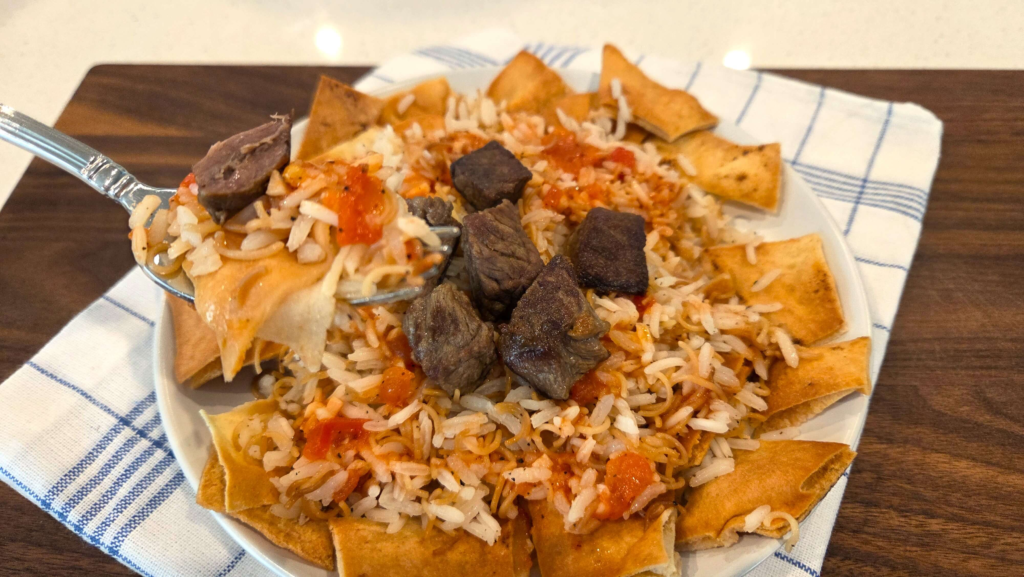 Layered Egyptian Fattah with toasted bread, vermicelli rice, tender beef, and garlic-vinegar tomato sauce.