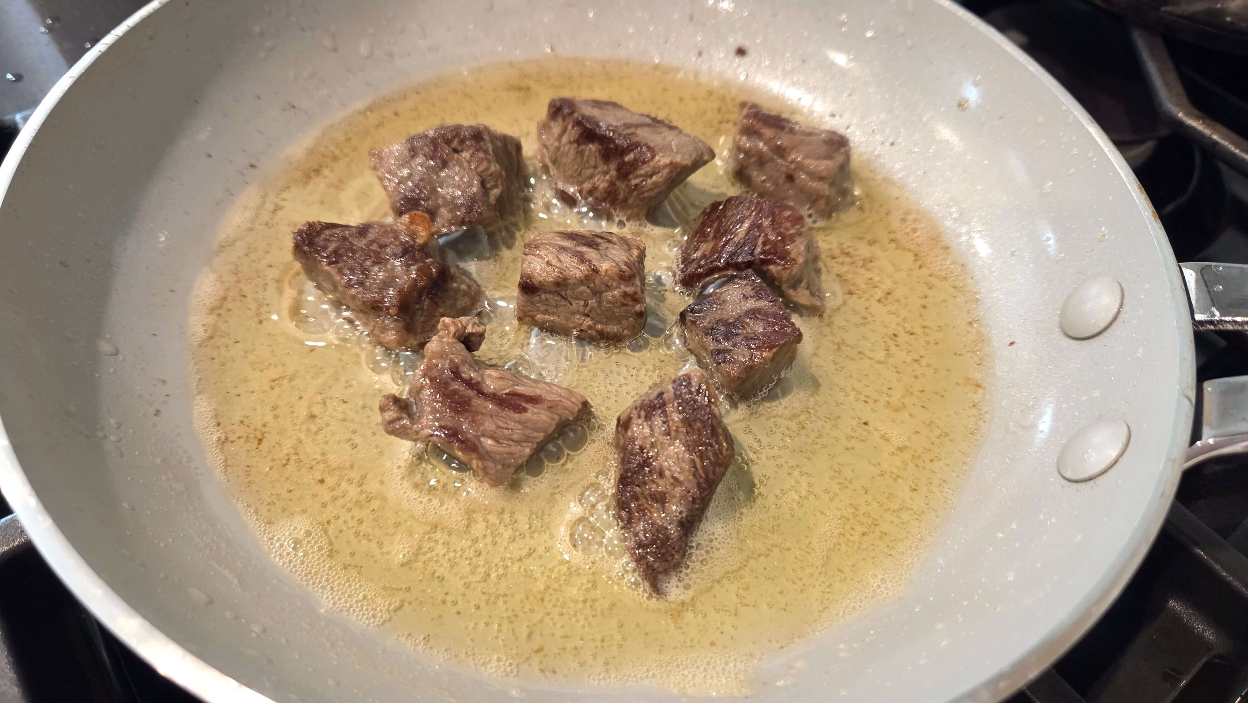 Tender cooked beef being browned in a skillet.