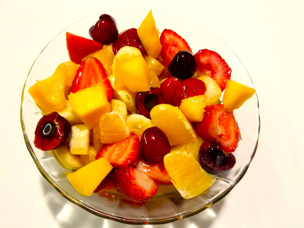 Fresh Egyptian fruit salad with mango, strawberries, oranges, cherries, banana, and sweet mango juice.
