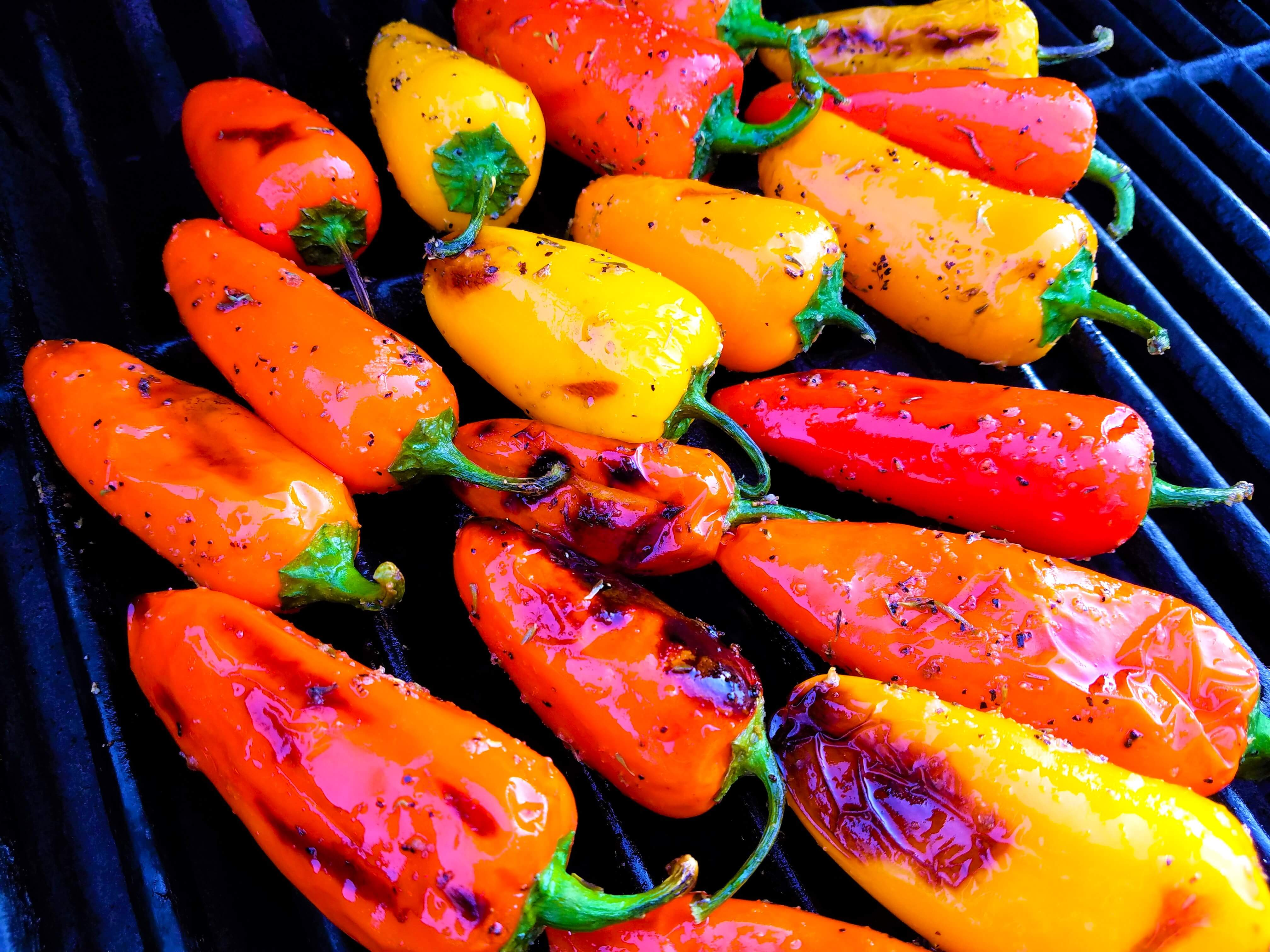 Mini sweet peppers being turned on the grill