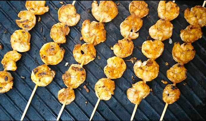 Shrimp kabobs grilling until lightly charred on a grill.