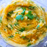 Mashed potato salad with fresh cilantro and lemon served in a bowl.