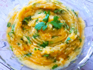 Mashed potato salad with fresh cilantro and lemon served in a bowl.
