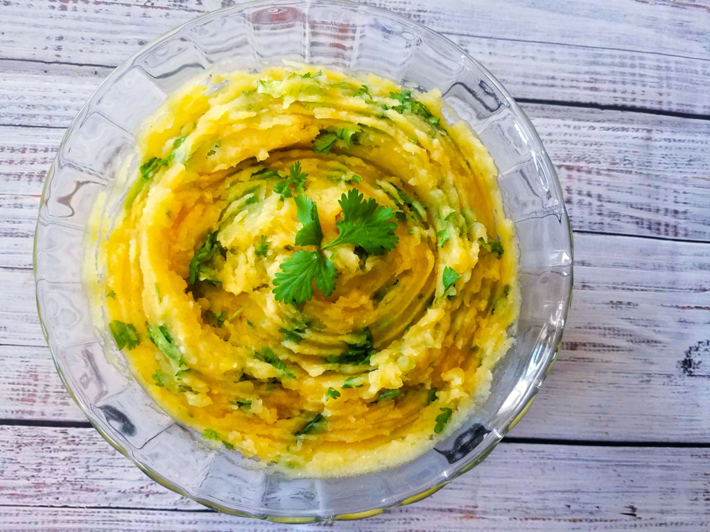 Mashed potato salad with lemon and cilantro served in a glass bowl.