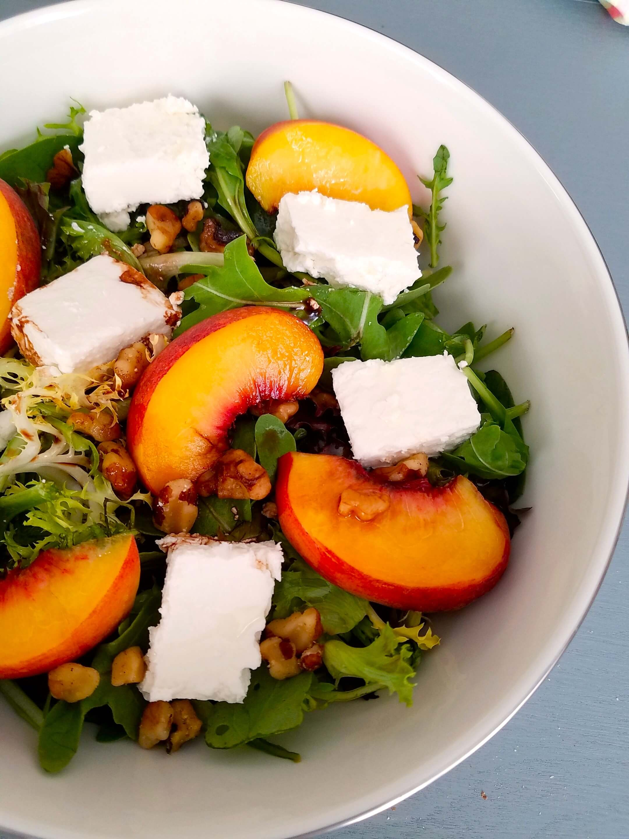 Peach feta salad with ripe peaches, creamy feta, crunchy walnuts, and mixed greens.