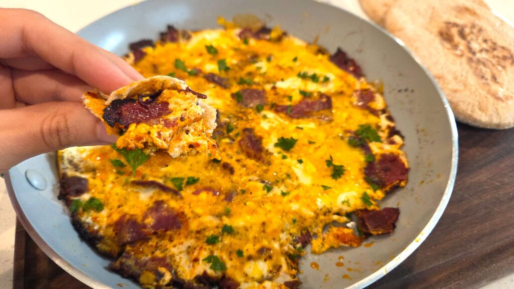 Soft scrambled eggs mixed with savory basturma in a skillet