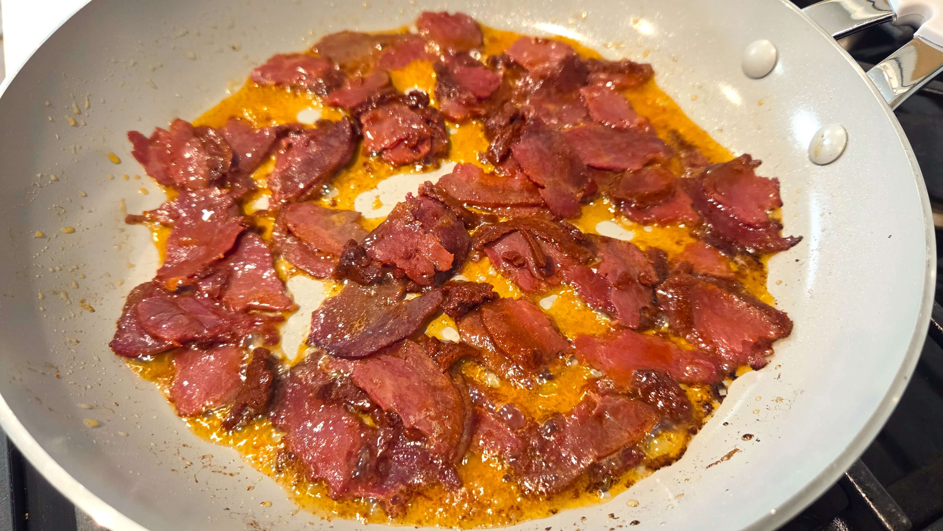 Basturma cooking in melted ghee in a skillet