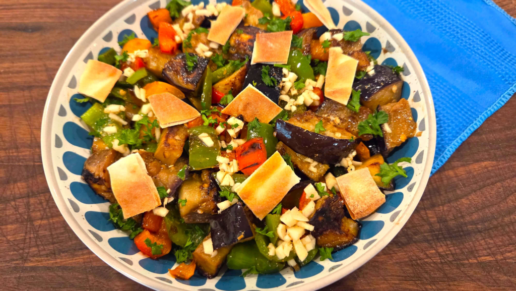 Egyptian eggplant salad with fried eggplant, red, orange, and green peppers, served with crispy roasted pita chips.