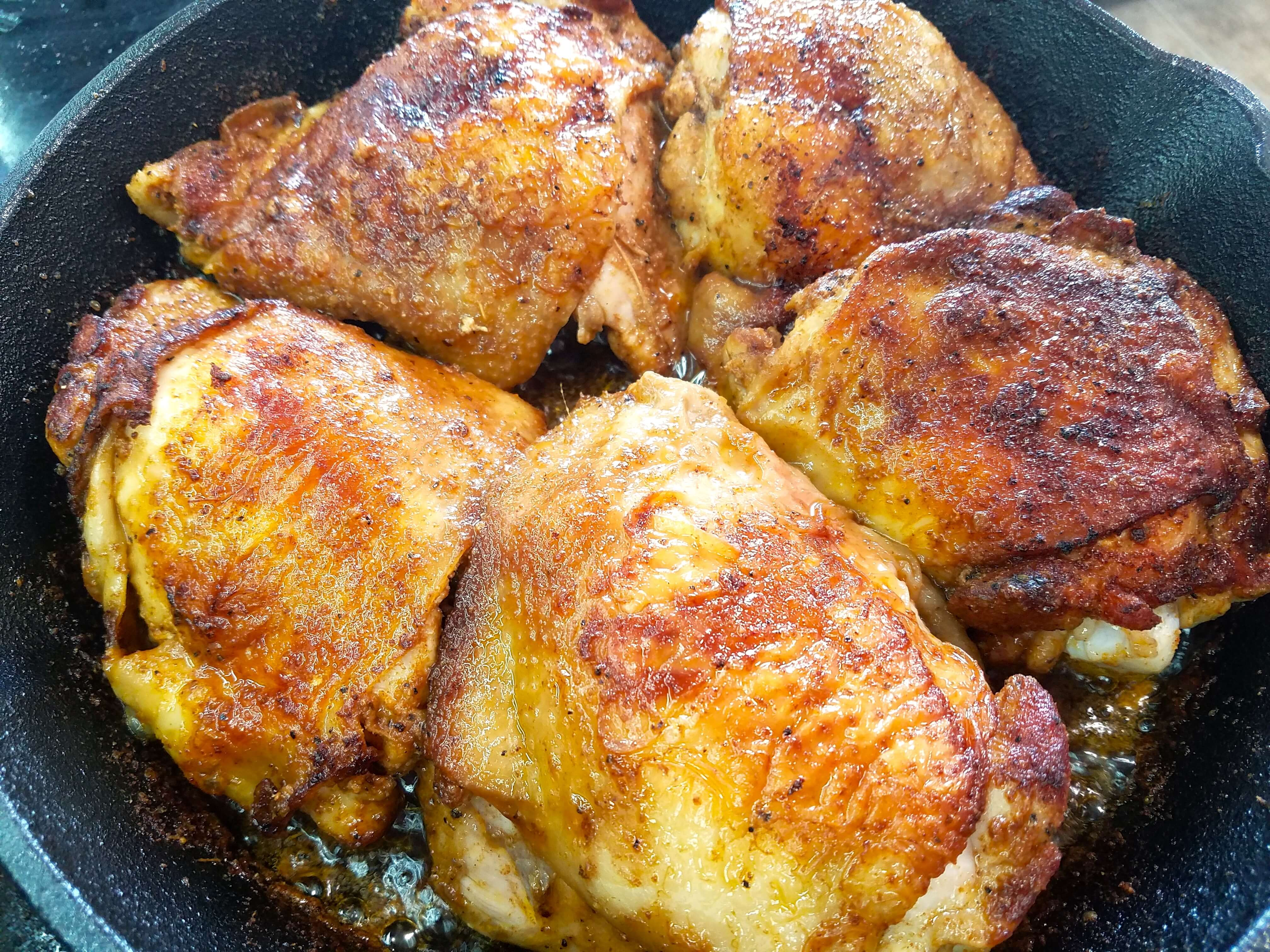 Golden chicken being flipped in a cast iron skillet