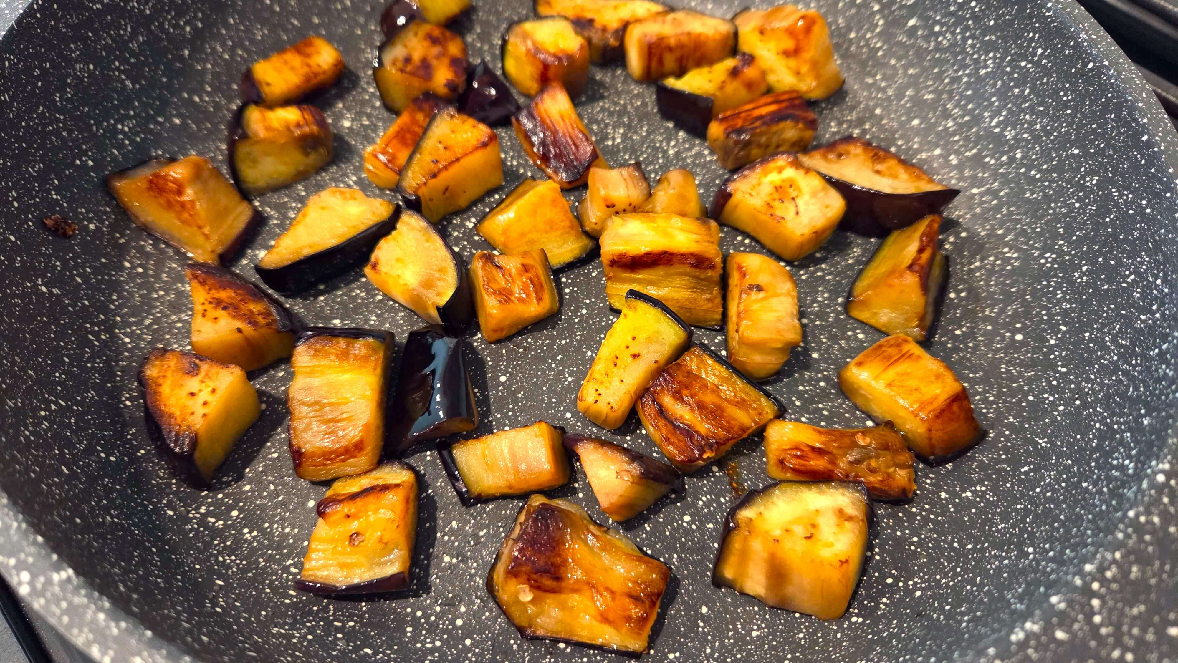 ggplant cubes frying in olive oil in a skillet until golden and tender.