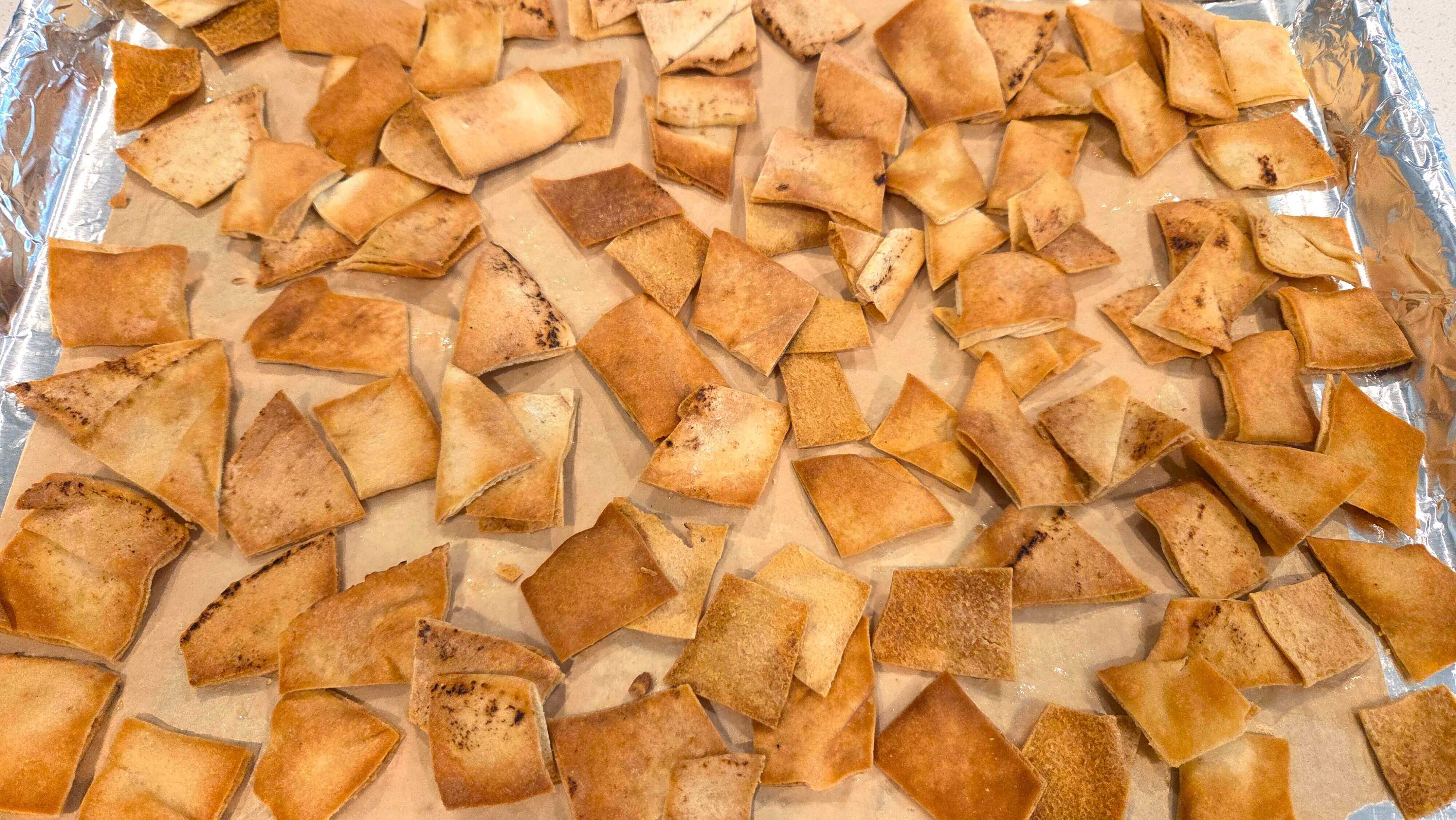 Pita bread triangles arranged on a baking sheet and roasted until golden and crisp.
