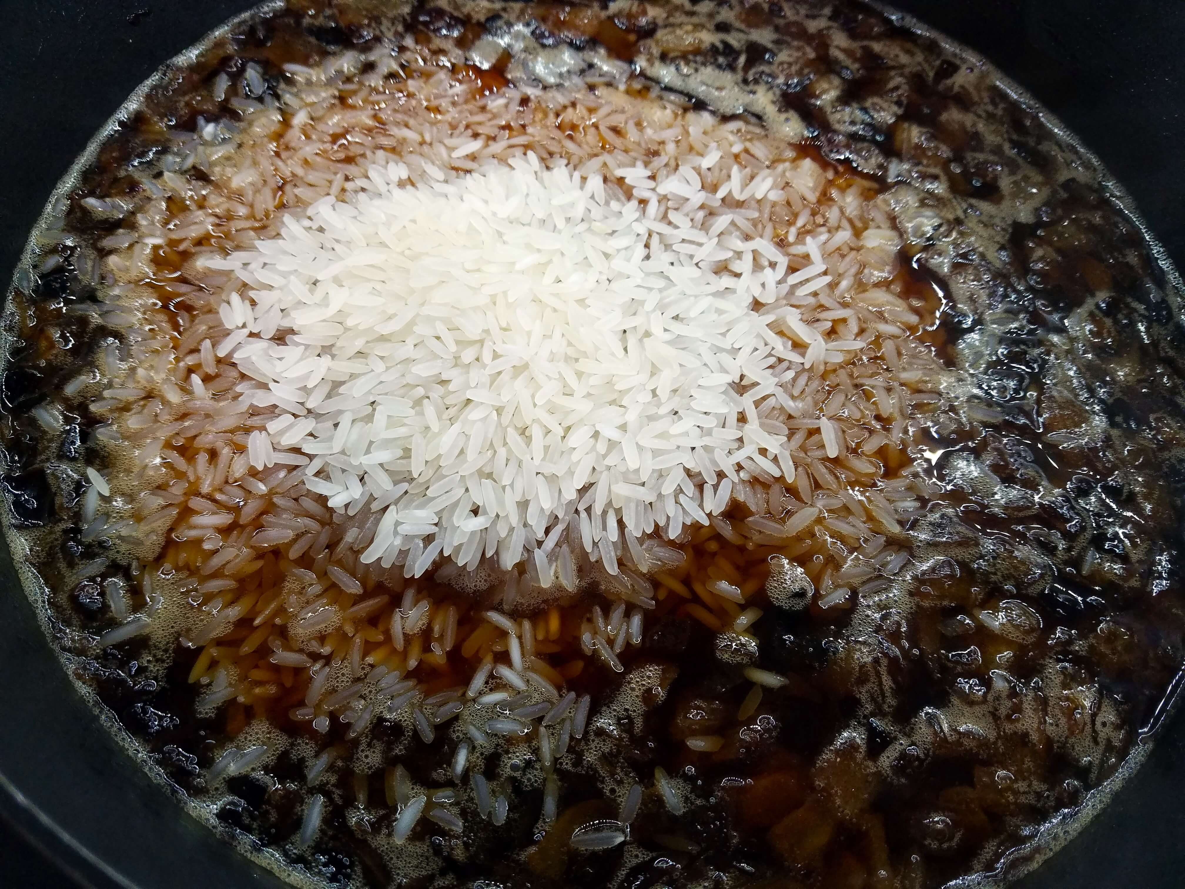 Rinsed rice added to the seasoned cooking liquid and browned onions