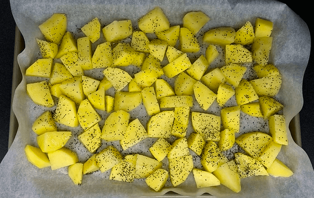 Cubed yellow potatoes tossed with olive oil, salt, and black pepper before roasting
