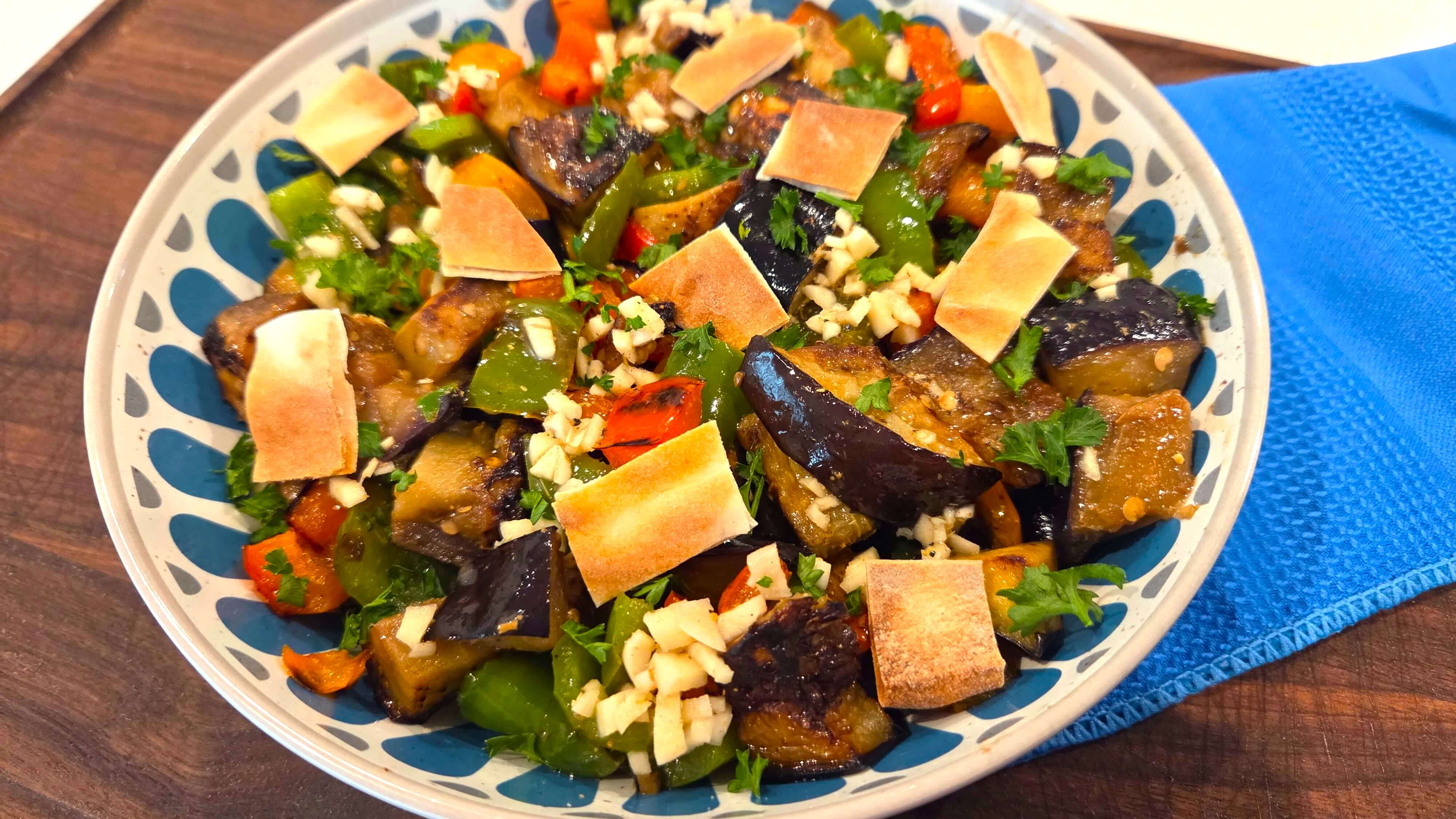 Egyptian eggplant salad with colorful peppers and fresh parsley served with crispy roasted pita chips.